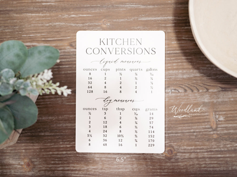 Kitchen conversions sign is 9 inches tall, 6.5 wide made of acrylic and comes with 2 acrylic feet to stand it up on. It features liquid and dry measurements and shows conversions for ounces, cups, pints, quarts, gallons, tsp, tbsp, cups and grams.